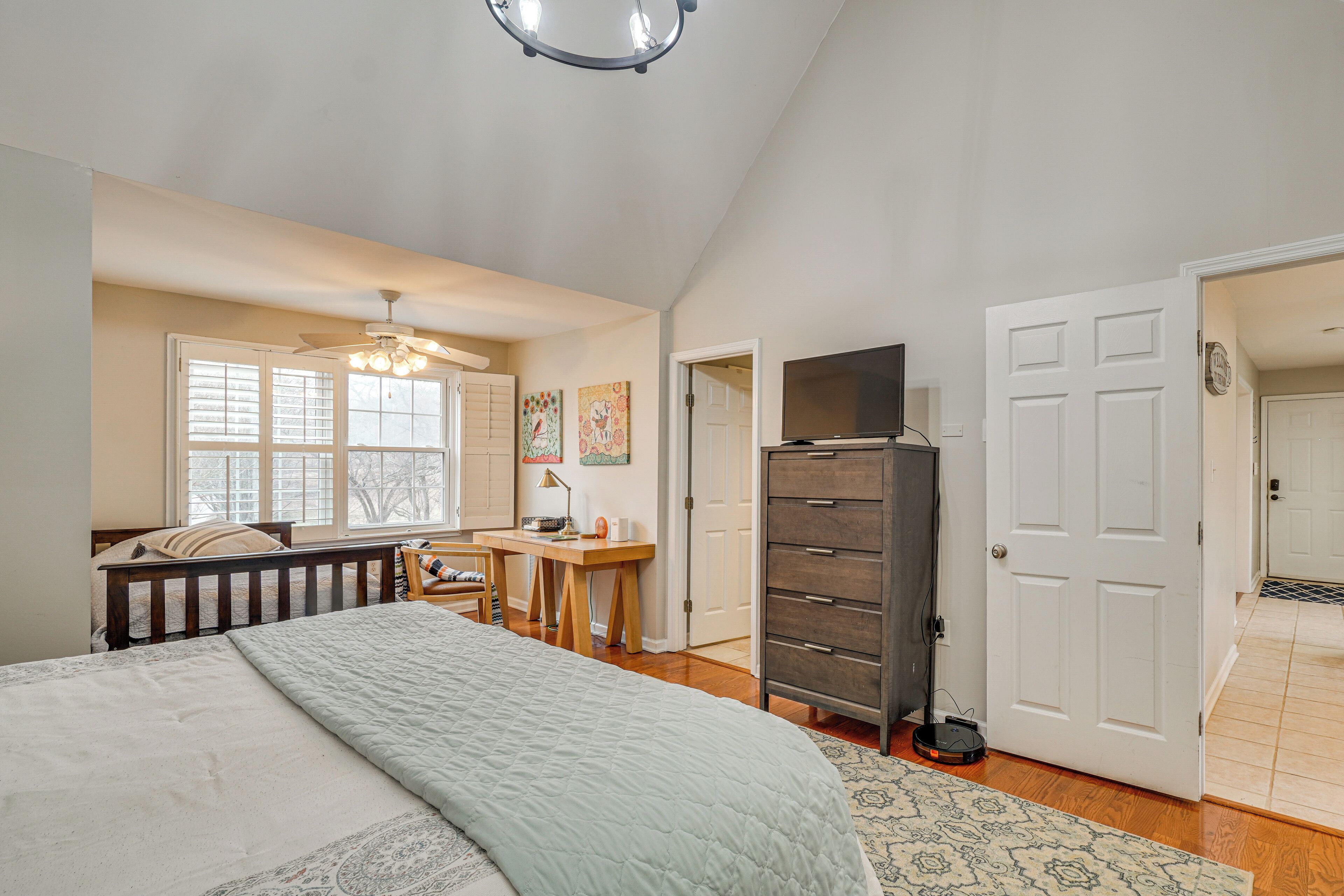 Une chambre à coucher comprenant un lit, un bureau, une commode et un téléviseur.