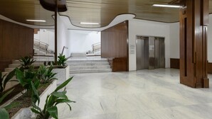 Eine großzügige Lobby mit Marmorboden, einer Treppe und einem Aufzug.