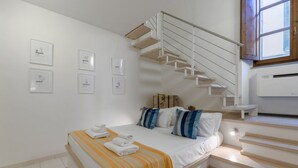 Ein Schlafzimmer mit Bett, Treppe und Wandbildern.