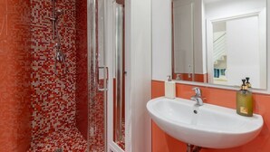 Ein Badezimmer mit Dusche, Waschbecken und Spiegel.