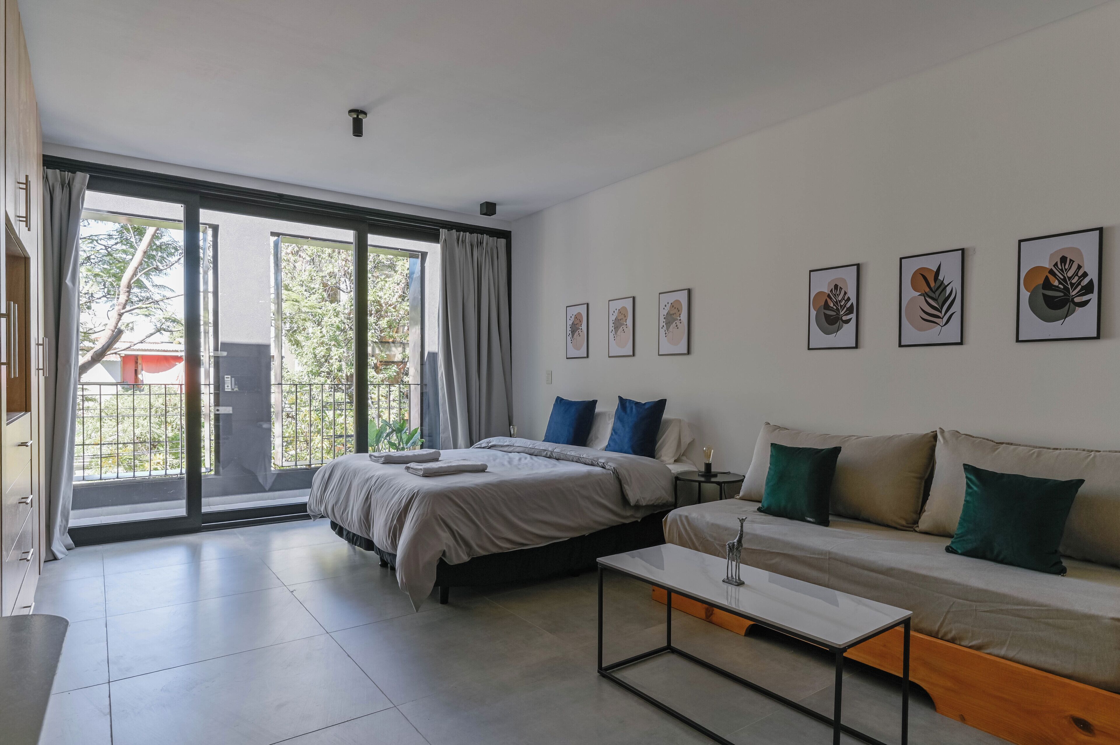 Ein modernes Schlafzimmer mit Bett, Sofa, Couchtisch und einem Balkon mit Blick.
