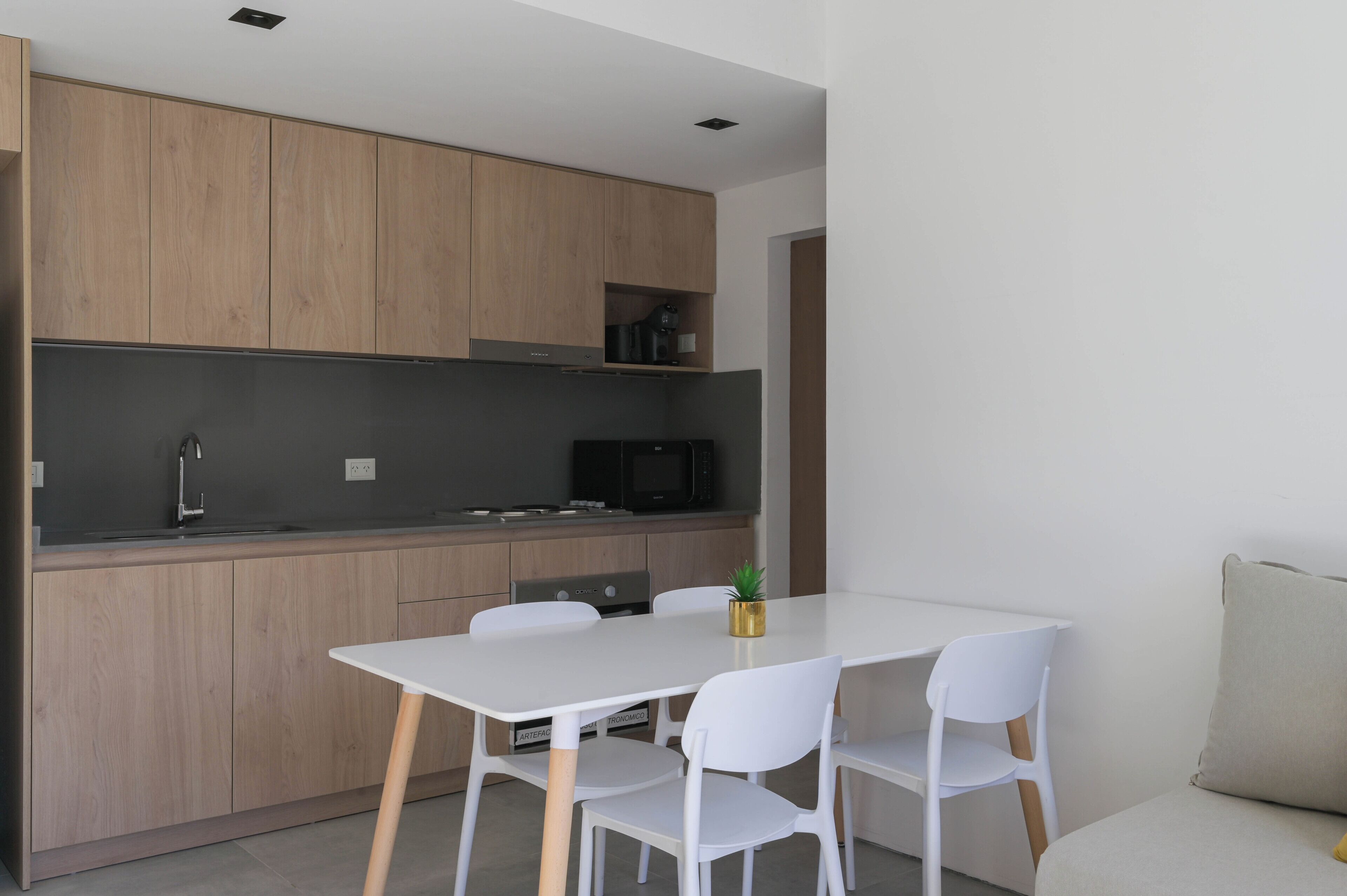 A modern kitchen with wooden cabinets, a white dining table, and chairs.