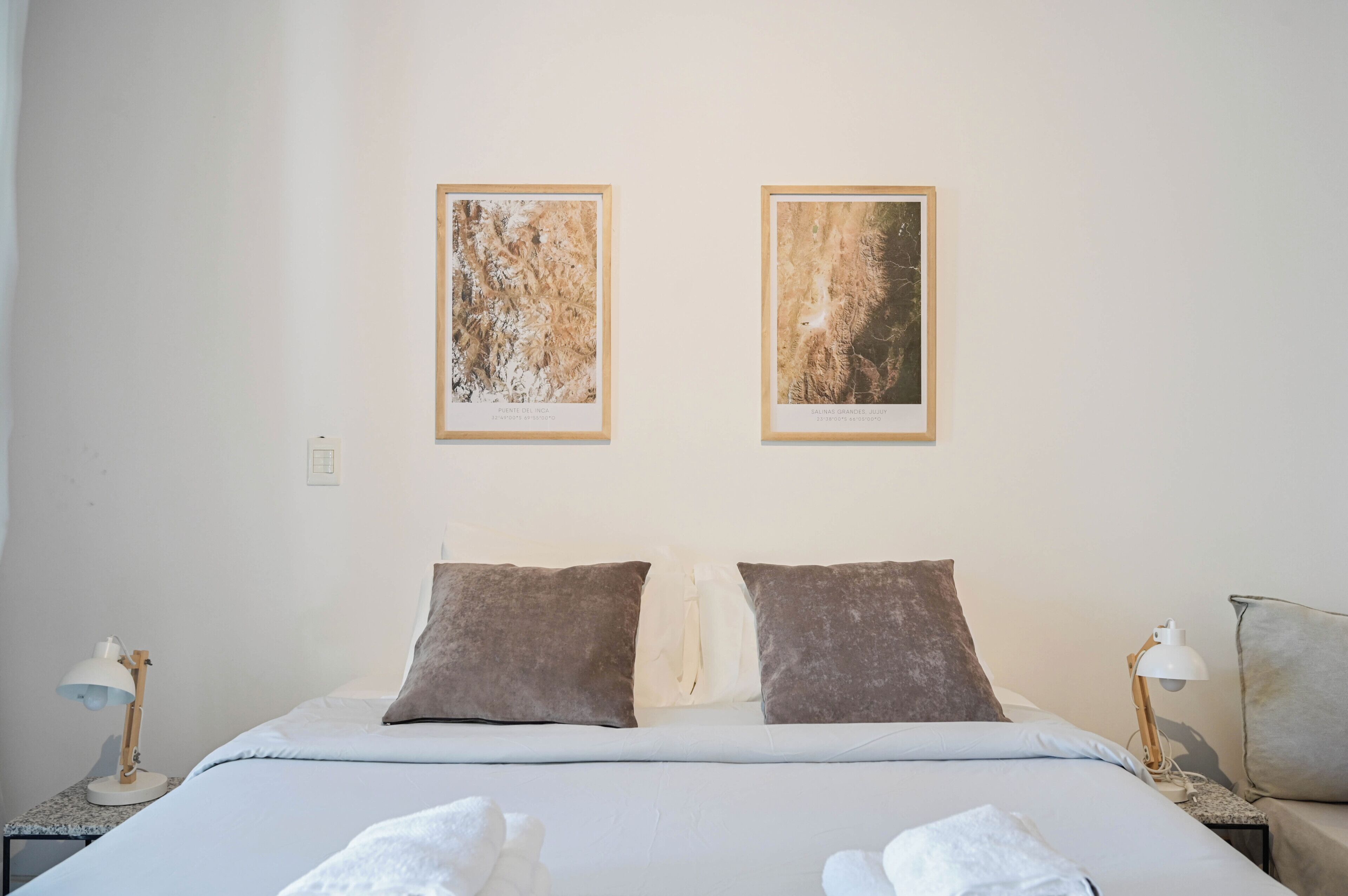 A neatly made bed with two pillows, a bedside lamp, and a framed picture on the wall.