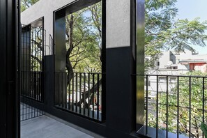 A balcony with a metal railing, a view of trees and buildings, and a clear sky. - MOT Black Ravignani (Buenos Aires)