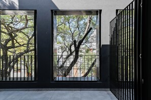 A view through a black metal gate with trees and a building in the background. - MOT Black Ravignani (Buenos Aires)