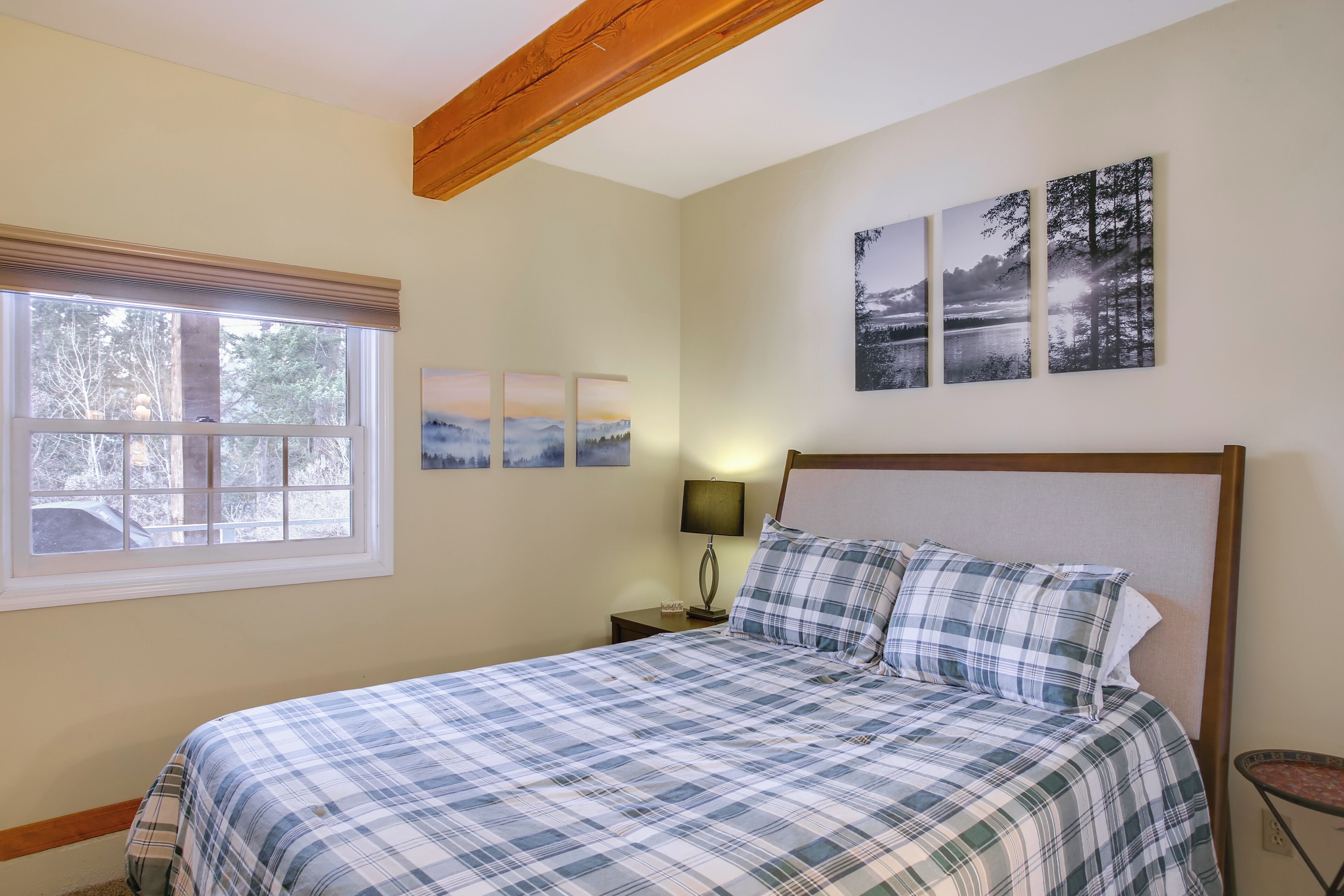 Un dormitorio con cama, ventana, mesita de noche y decoración en la pared.