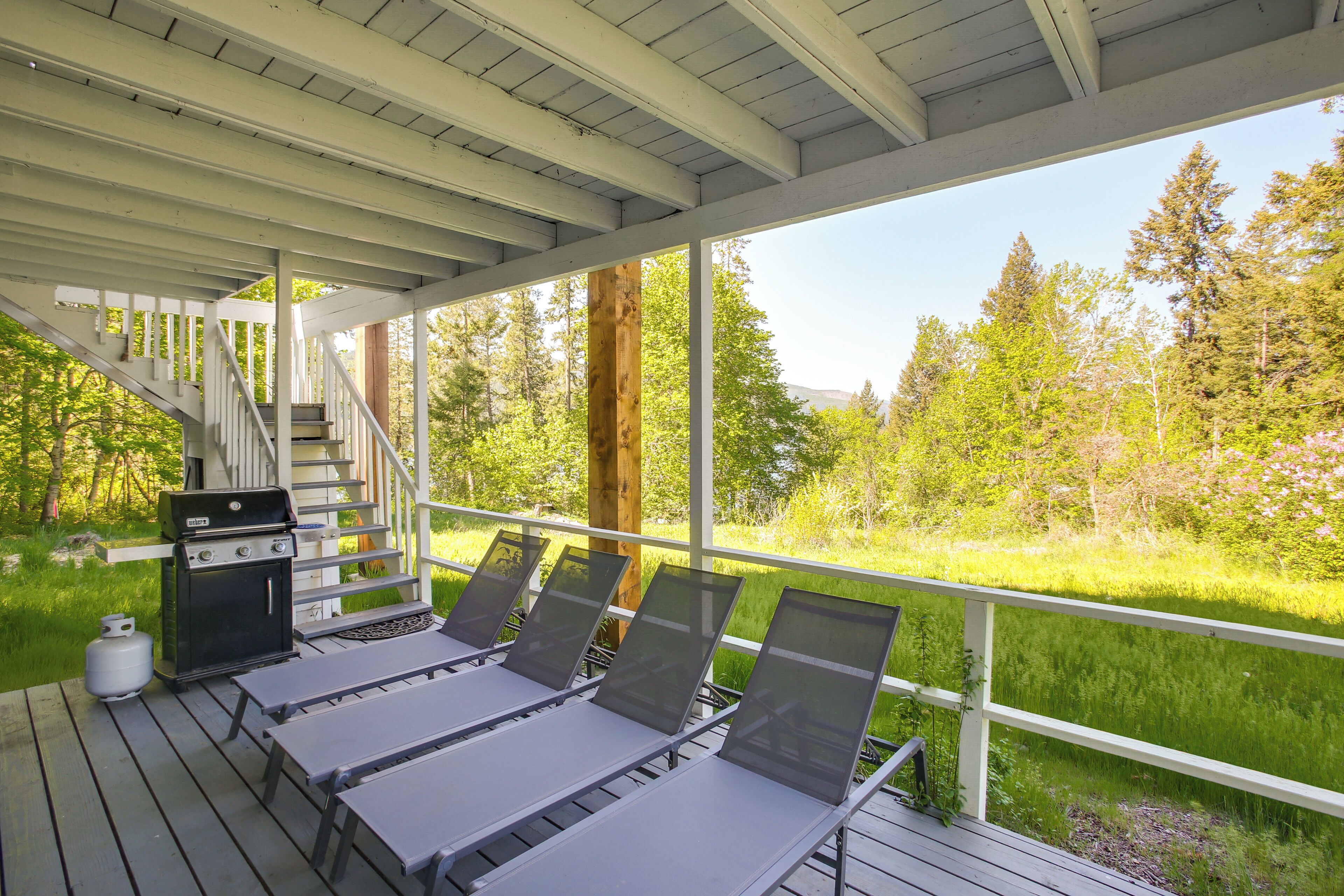 A covered deck with outdoor seating, a grill, and a staircase leading to an upper level.