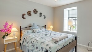 Un dormitorio con cama, mesitas de noche, una ventana y adornos en la pared.