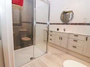 A modern bathroom with a glass shower enclosure, a toilet, a sink, and a mirror. - Cairndhu (Bo'ness)