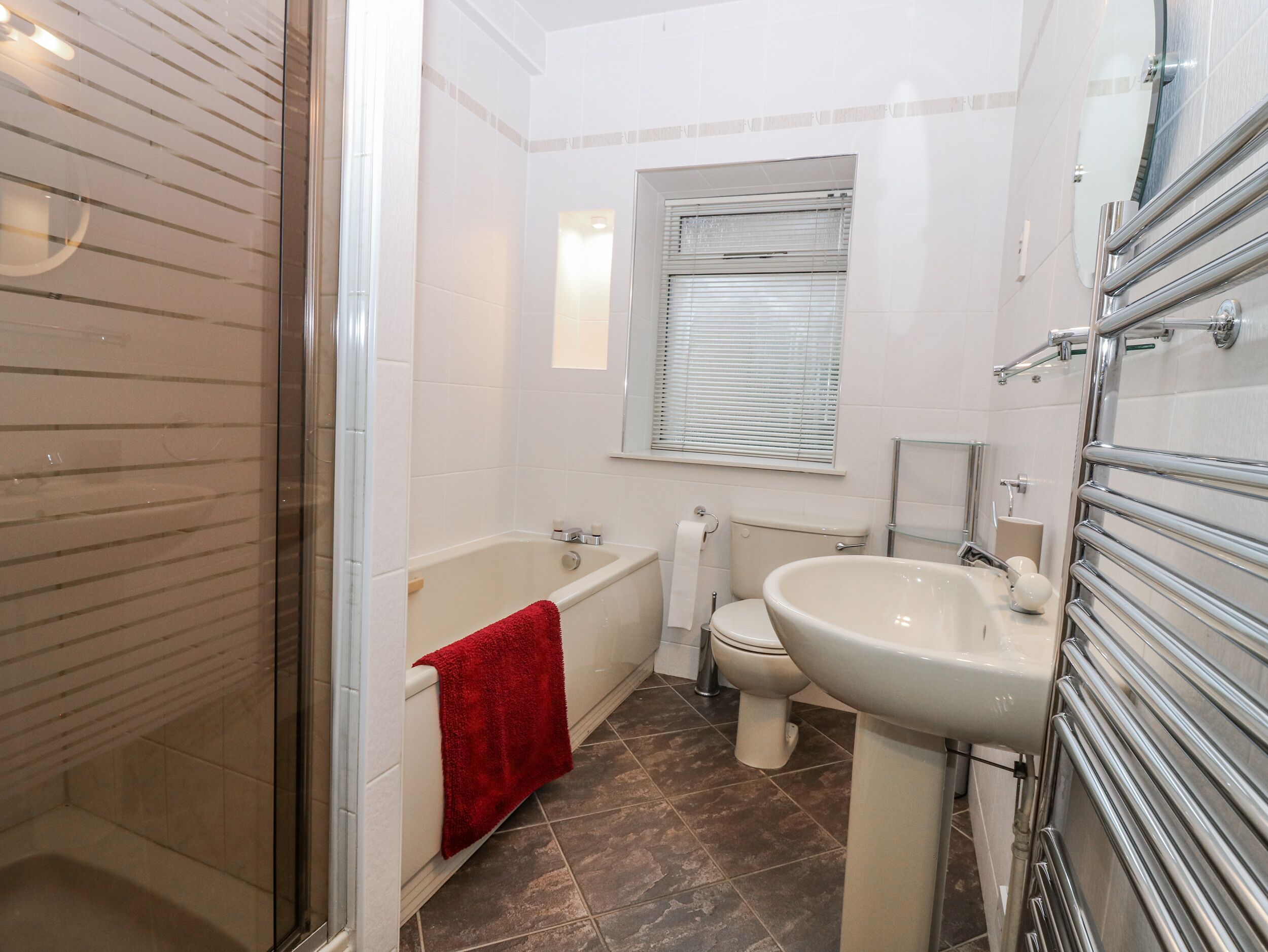 Un bagno moderno con cabina doccia in vetro, vasca da bagno, toilette e lavandino.