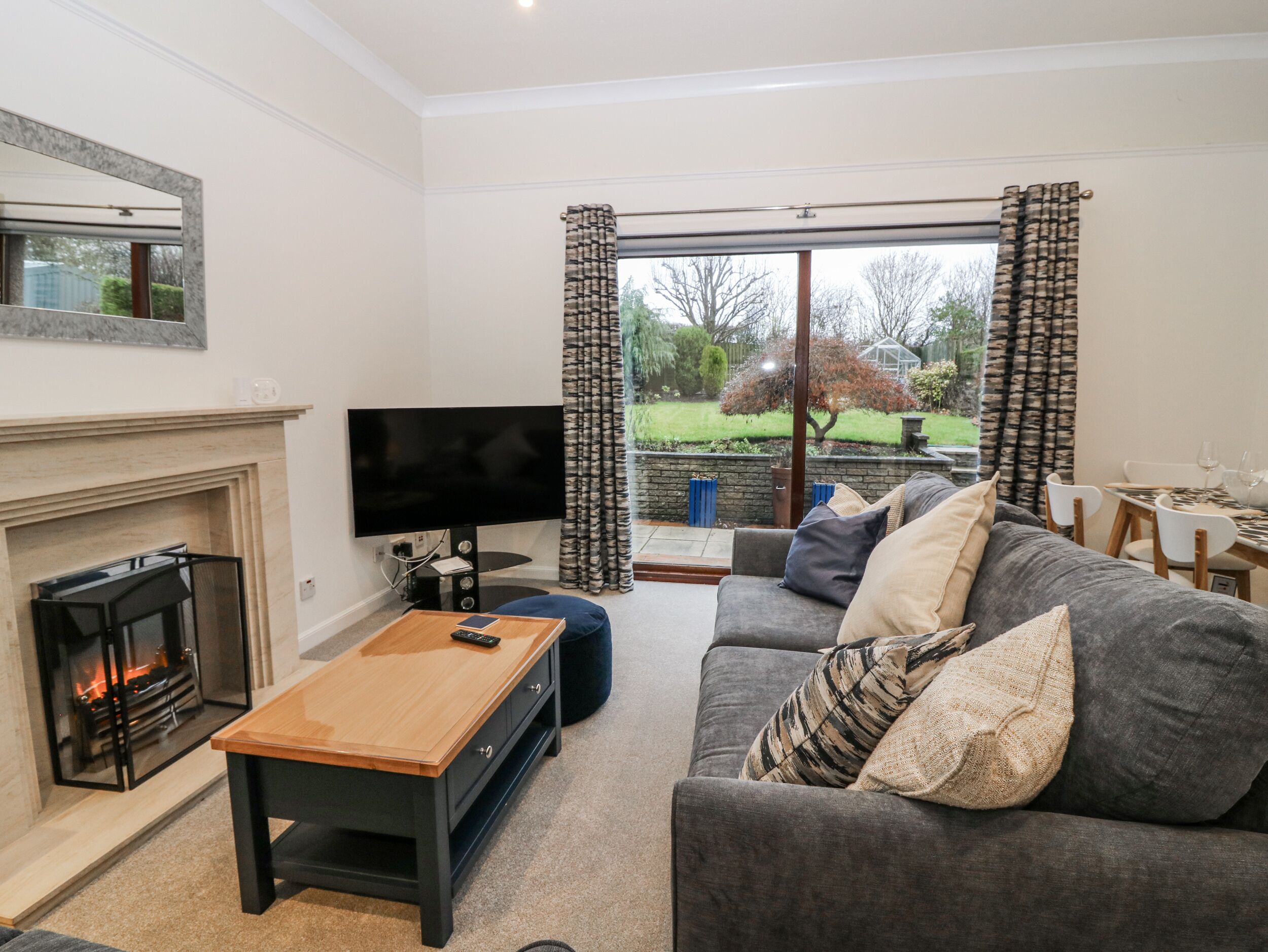 A living room with a fireplace, a television, a sofa, and a dining area with a table and chairs.