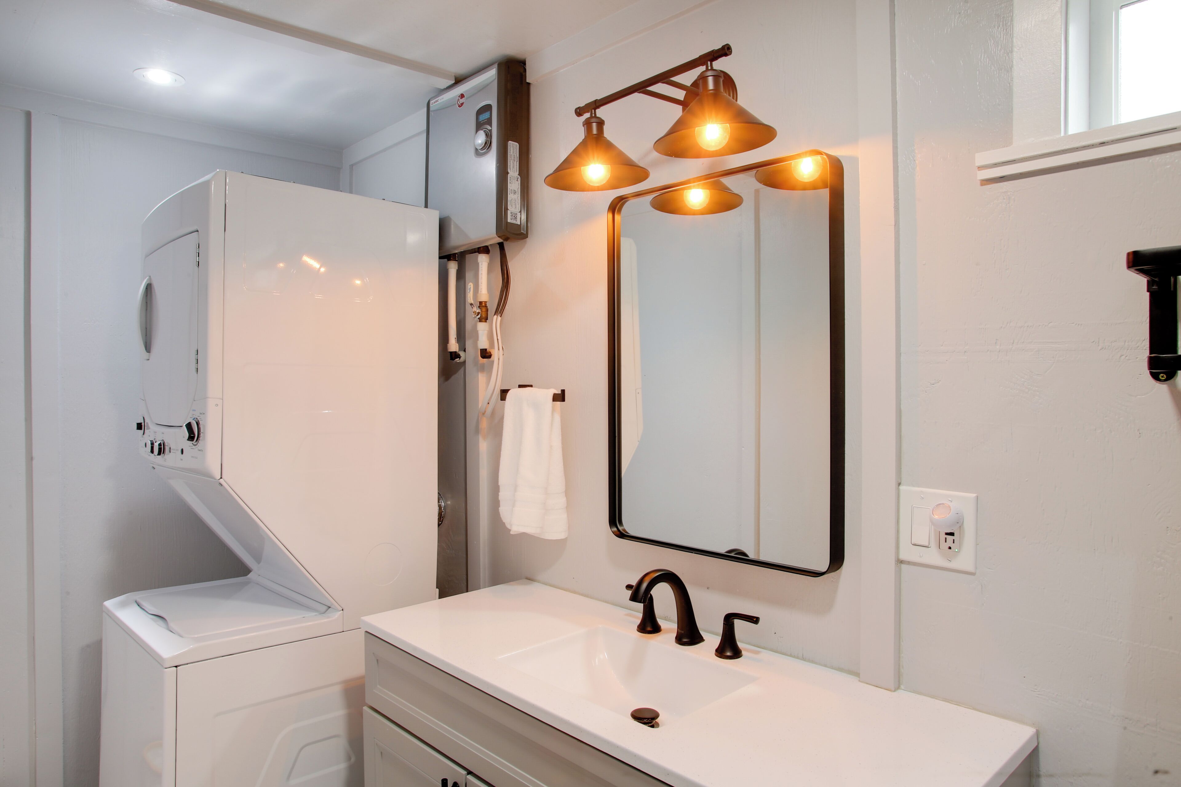 Une salle de bain avec un lavabo blanc, un miroir et un radiateur fixé au mur.
