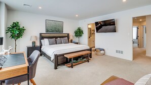 A modern bedroom with a large bed, bedside tables, a desk, and a TV mounted on the wall. - Half-mi to the Triangle! Chic Emmaus Townhome (Emmaus)