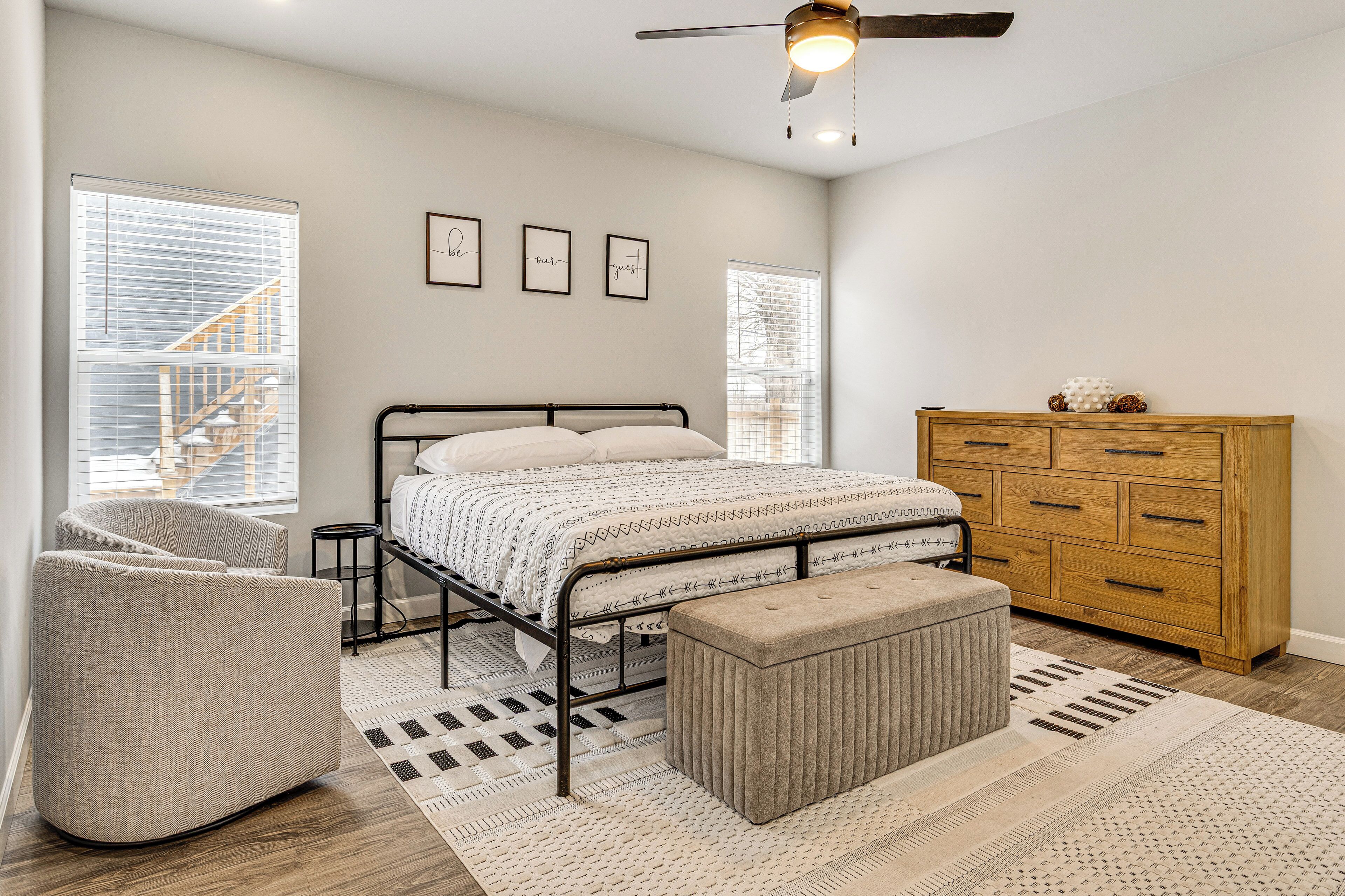 A bedroom with a bed, a wooden dresser, a chair, and a ceiling fan.