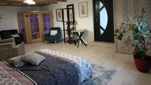 A cozy room with a bed, a chair, a small table, and a potted plant.