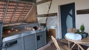 A spa area with a hot tub, wooden deck, and a small seating area with a table and chairs.