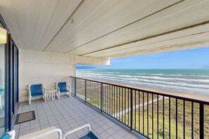 A balcony with a view of the ocean, two chairs, and a small table. - Shorefront Resort Retreat: Suntide III - Unit 1002 (South Padre Island)
