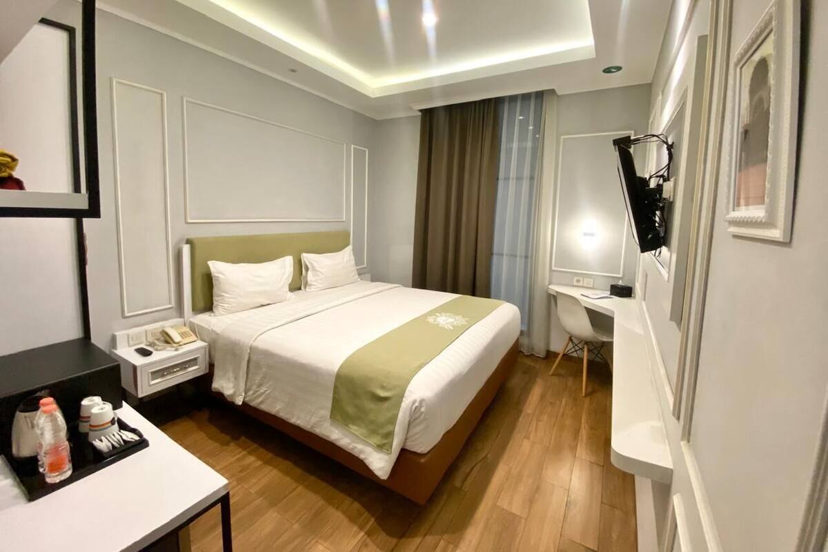 Ein Hotelzimmer mit Bett, Nachttisch, Schreibtisch und Spiegel.