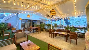 An indoor dining area with wooden tables and chairs, hanging lights, and a large tent structure. - Dafam Enkadeli Thamrin Jakarta (Jakarta)