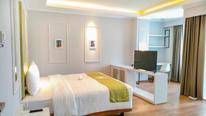 A modern hotel room with a bed, a desk with a television, and artwork on the walls. - Dafam Enkadeli Thamrin Jakarta (Jakarta)