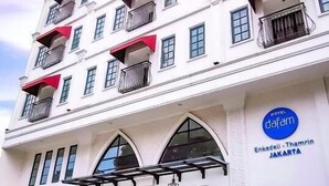 A multi-story hotel with balconies, a prominent entrance with a glass facade, and a sign indicating its location in Jakarta. - Dafam Enkadeli Thamrin Jakarta (Jakarta)