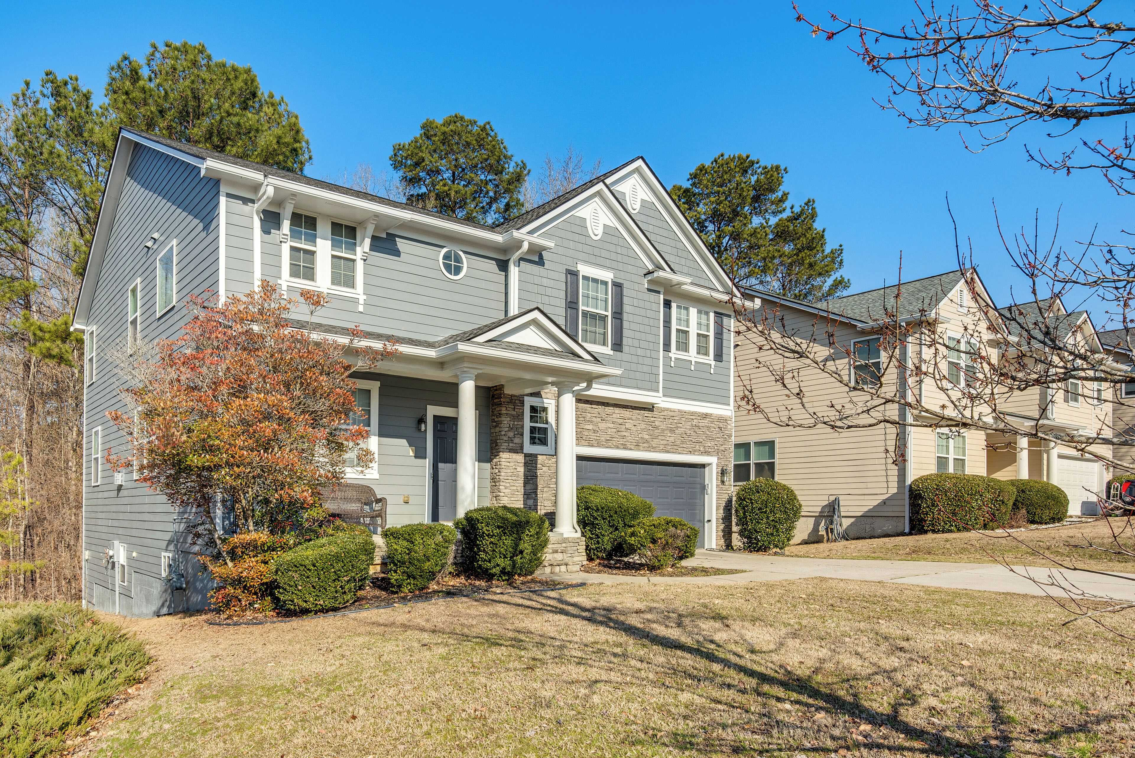 A two-story house with a front porch, a garage, and a well-maintained lawn.