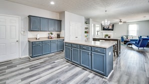 A modern kitchen with grey cabinets, a central island, and a dining area with blue chairs. - Great for Gatherings! Elegant Atlanta Retreat (Atlanta)