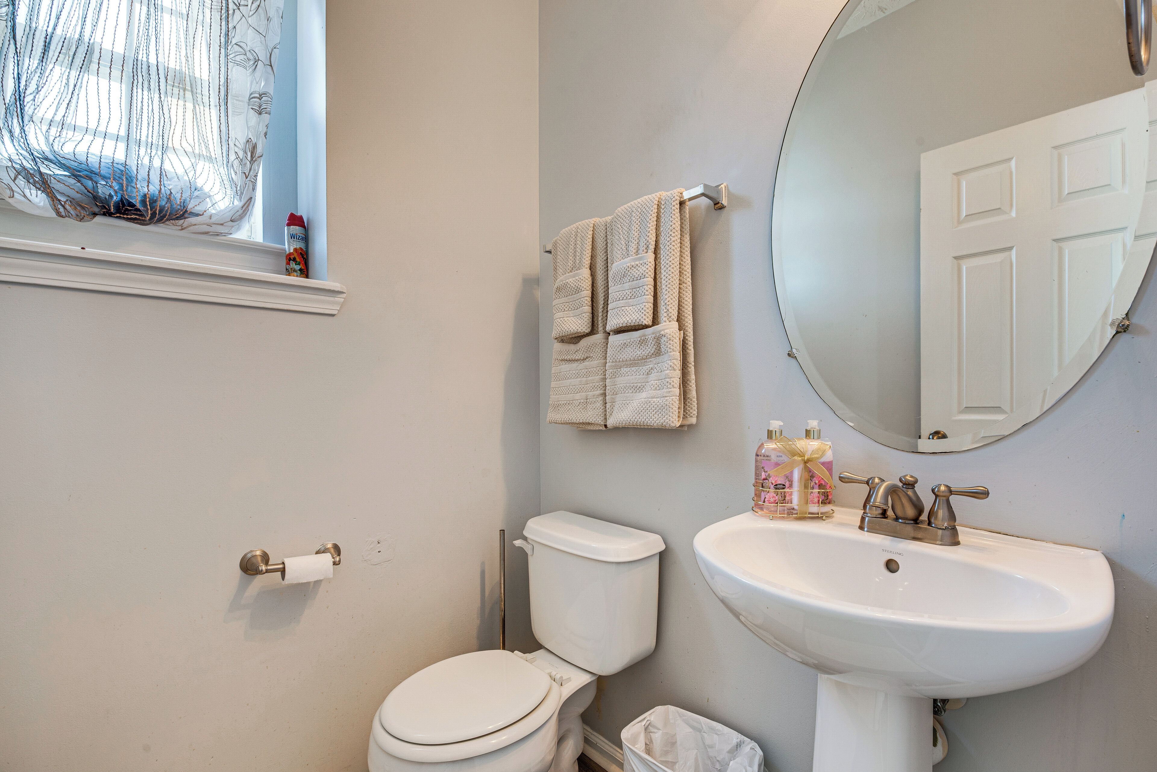Ein Badezimmer mit Toilette, Waschbecken und einem Fenster mit Vorhängen.