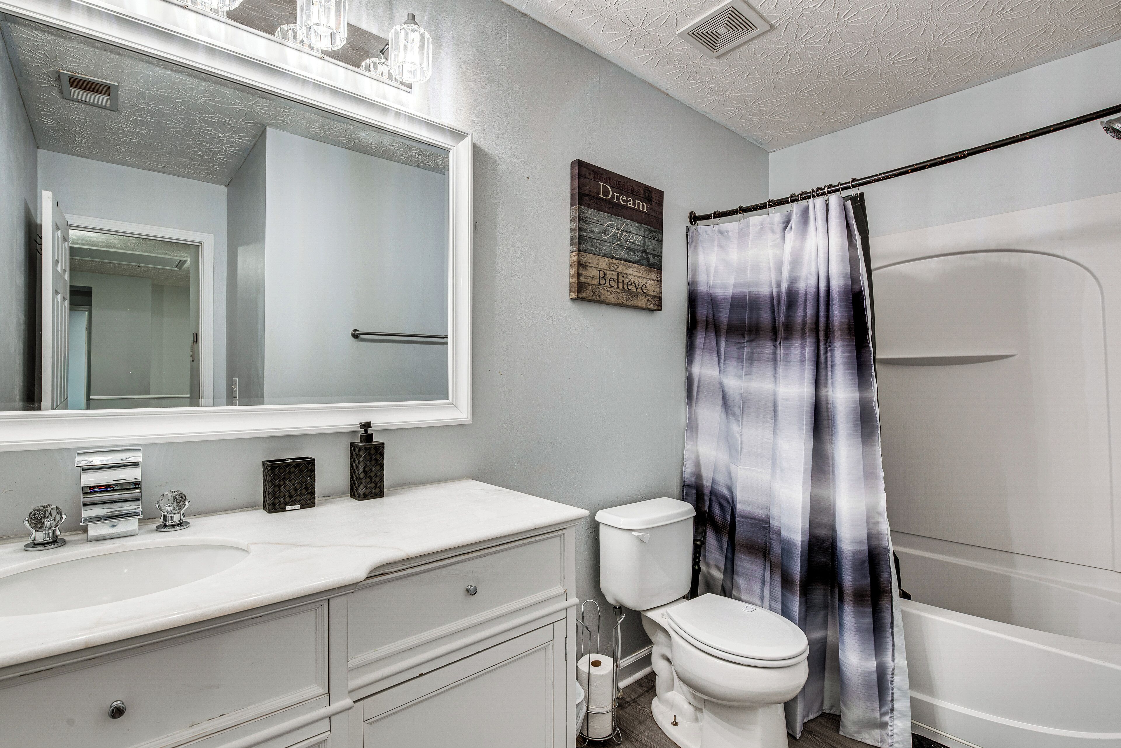 A bathroom with a white sink, toilet, and shower curtain.