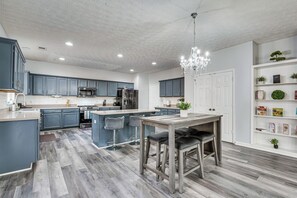 Une cuisine moderne avec des meubles bleus, un îlot central et un lustre.