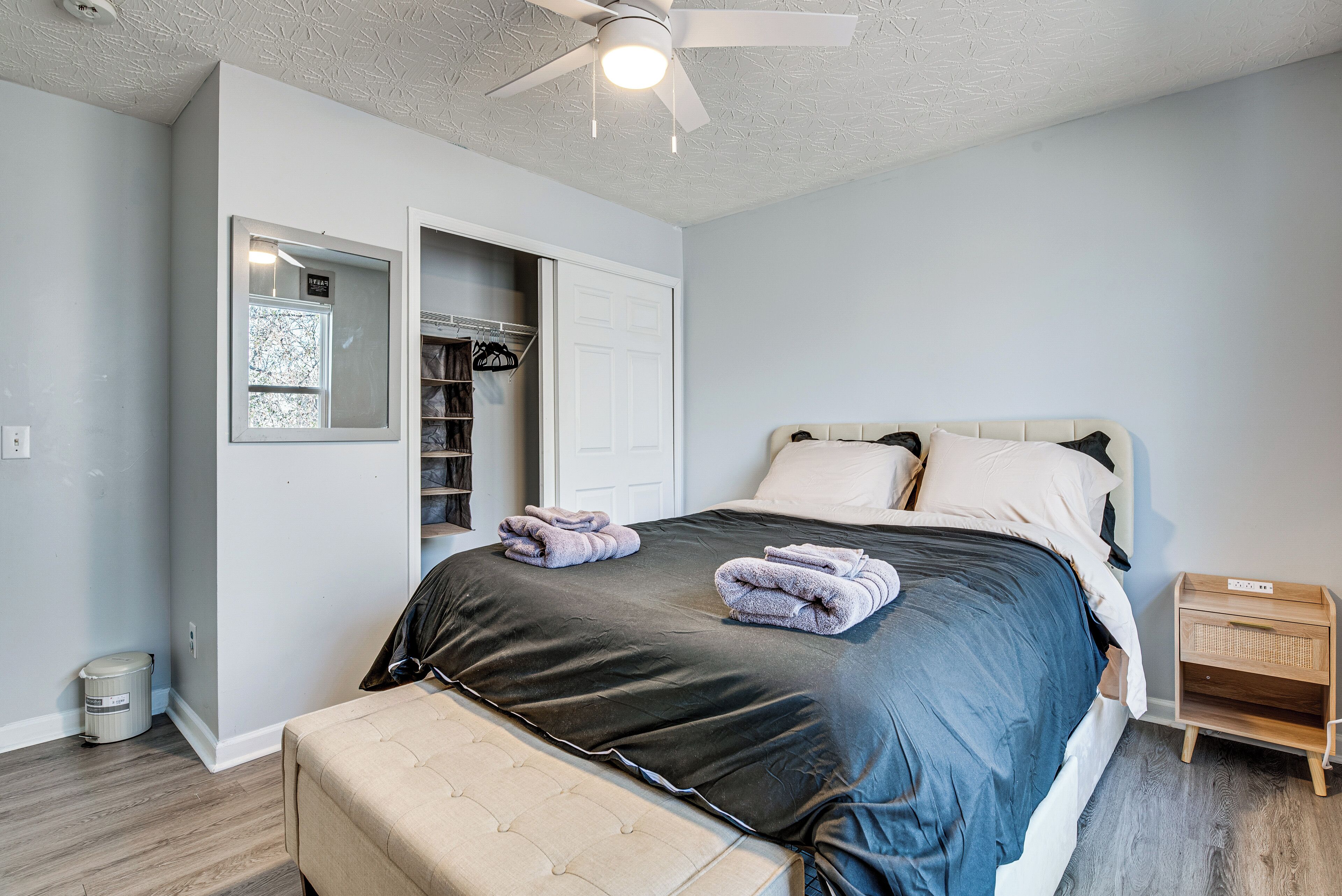 Une chambre à coucher comprenant un lit, un ventilateur de plafond, une armoire et une table de chevet.