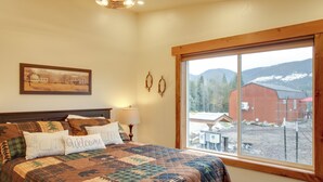 Ein Schlafzimmer mit einem großen Bett, einem Fenster mit Blick auf einen roten Bauernhof und Berge, sowie einem Gemälde an der Wand.