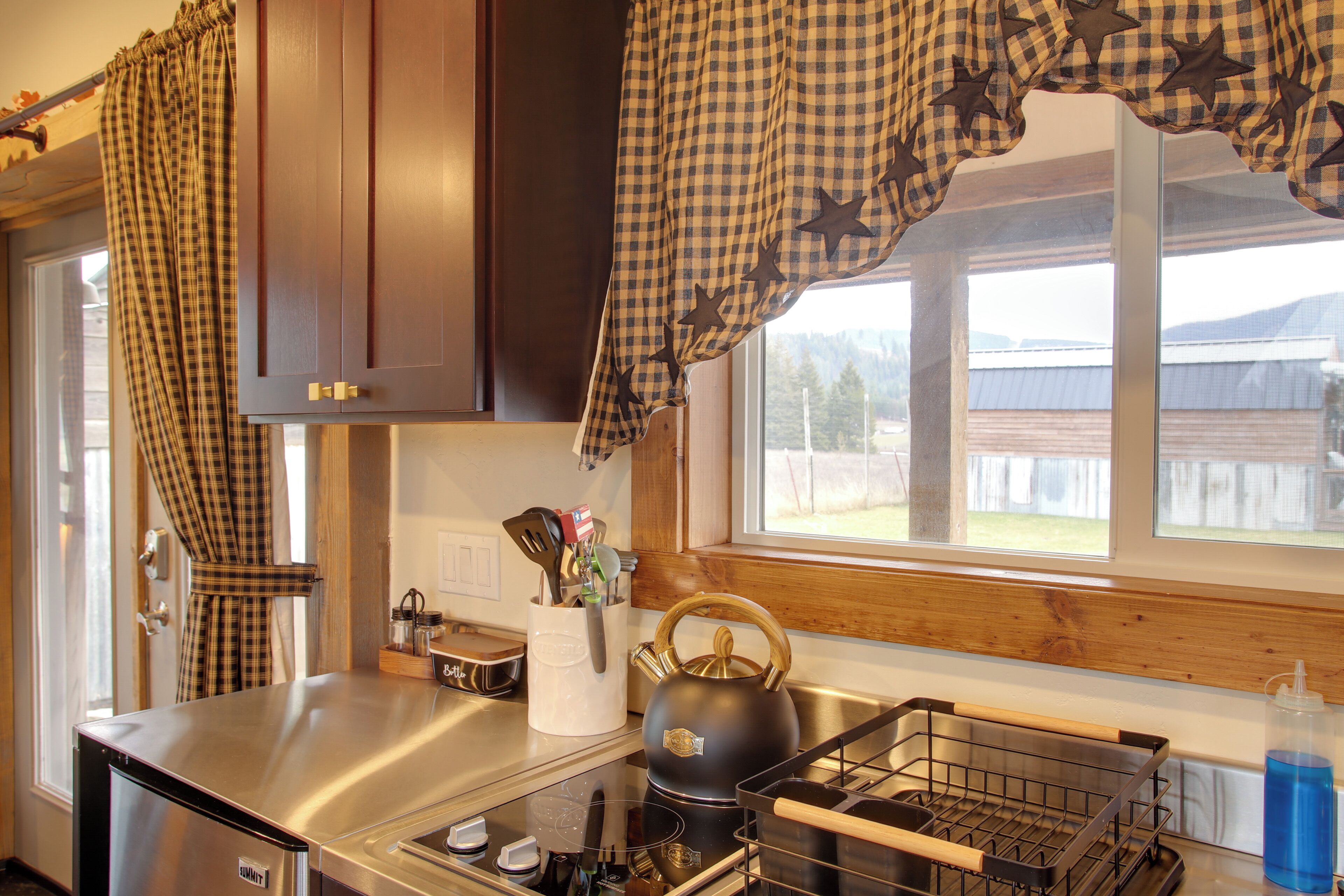 A kitchen with a stainless steel refrigerator, a kettle, and a sink.