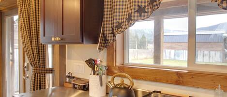 A kitchen with a stainless steel refrigerator, a kettle, and a sink.