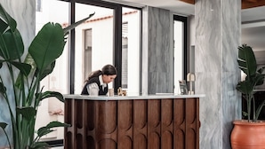 A reception desk with a marble wall and wooden paneling, large windows, and potted plants. - Boutique Nest Luxury 2BR Serviced Apartment (Cairo Governorate)