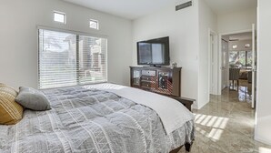 Una camera da letto con un letto, una televisione su un comò e una ventola a soffitto.