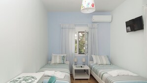 A small, well-lit room with two single beds, a desk, and a chair. - Naoussa Apricot Garden, 5' to Center, 5' to Beach (Naousa)