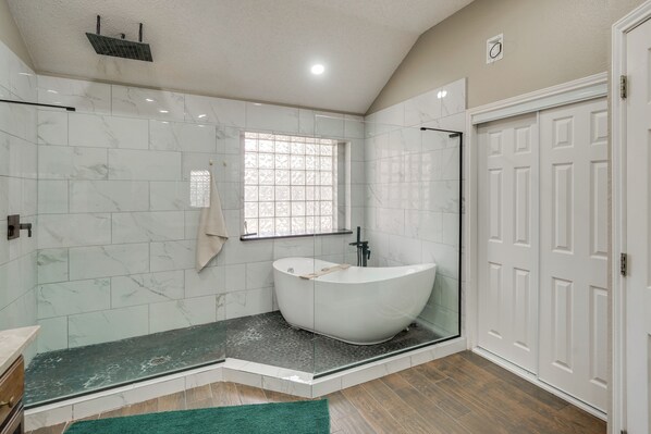 A modern bathroom with a freestanding bathtub, a glass shower enclosure, and a large window with a decorative grid pattern. - 5 Mi to Dtwn Odessa: Modern Home! (Odessa)