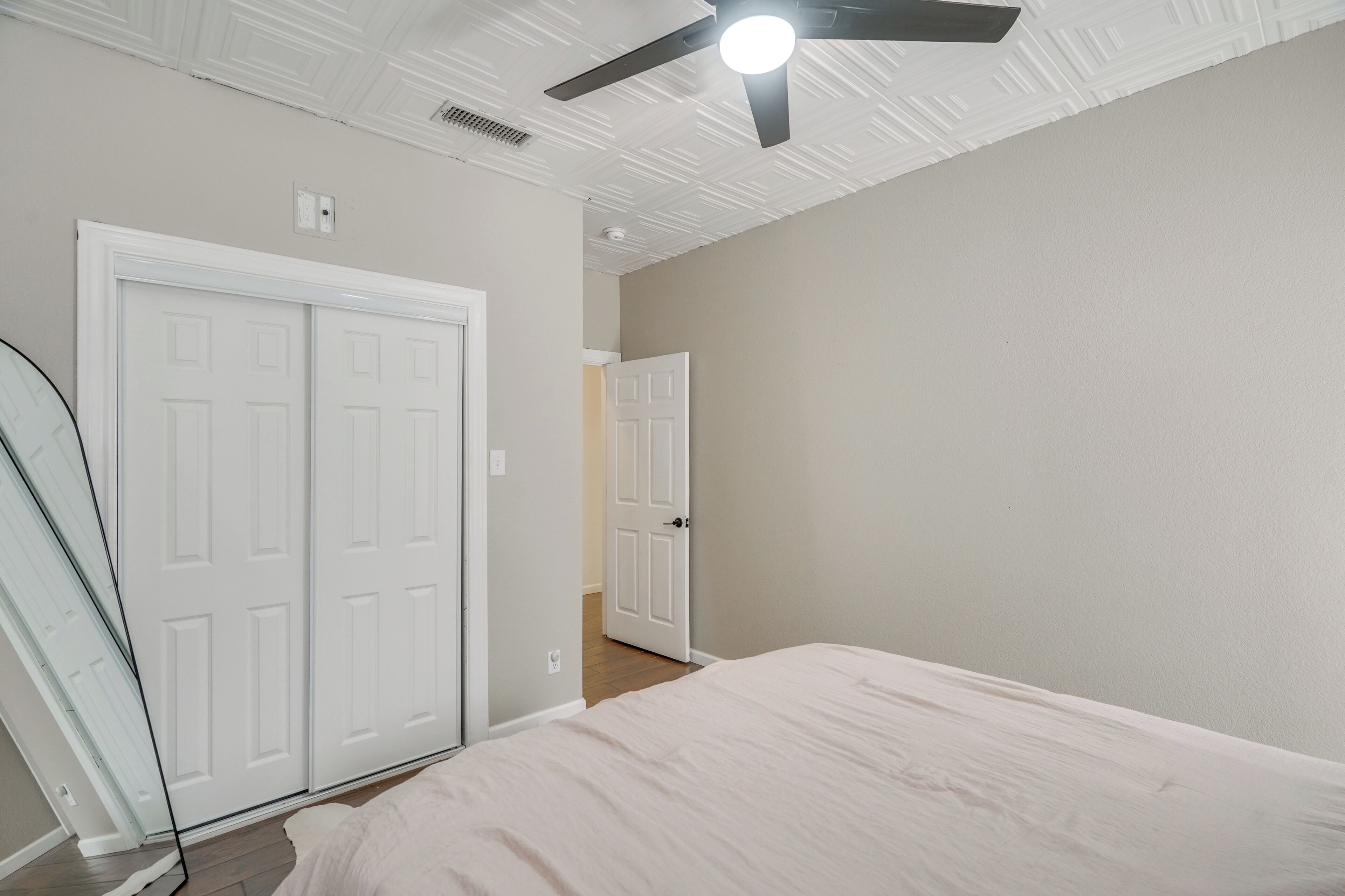 Un dormitorio con cama, ventilador de techo y una puerta blanca.