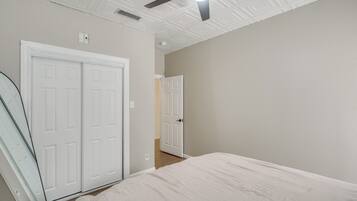 Un dormitorio con cama, ventilador de techo y una puerta blanca.