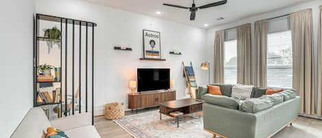 A modern living room with a sofa, television, and decorative items.