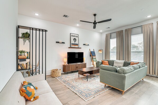 A modern living room with a sofa, television, and decorative items. - 4 Mi to Dtwn: Wfh-friendly Retreat in Houston (Houston)