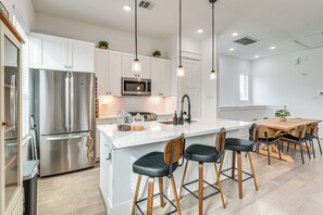A modern kitchen with stainless steel appliances, a white countertop, and wooden bar stools. - 4 Mi to Dtwn: Wfh-friendly Retreat in Houston (Houston)