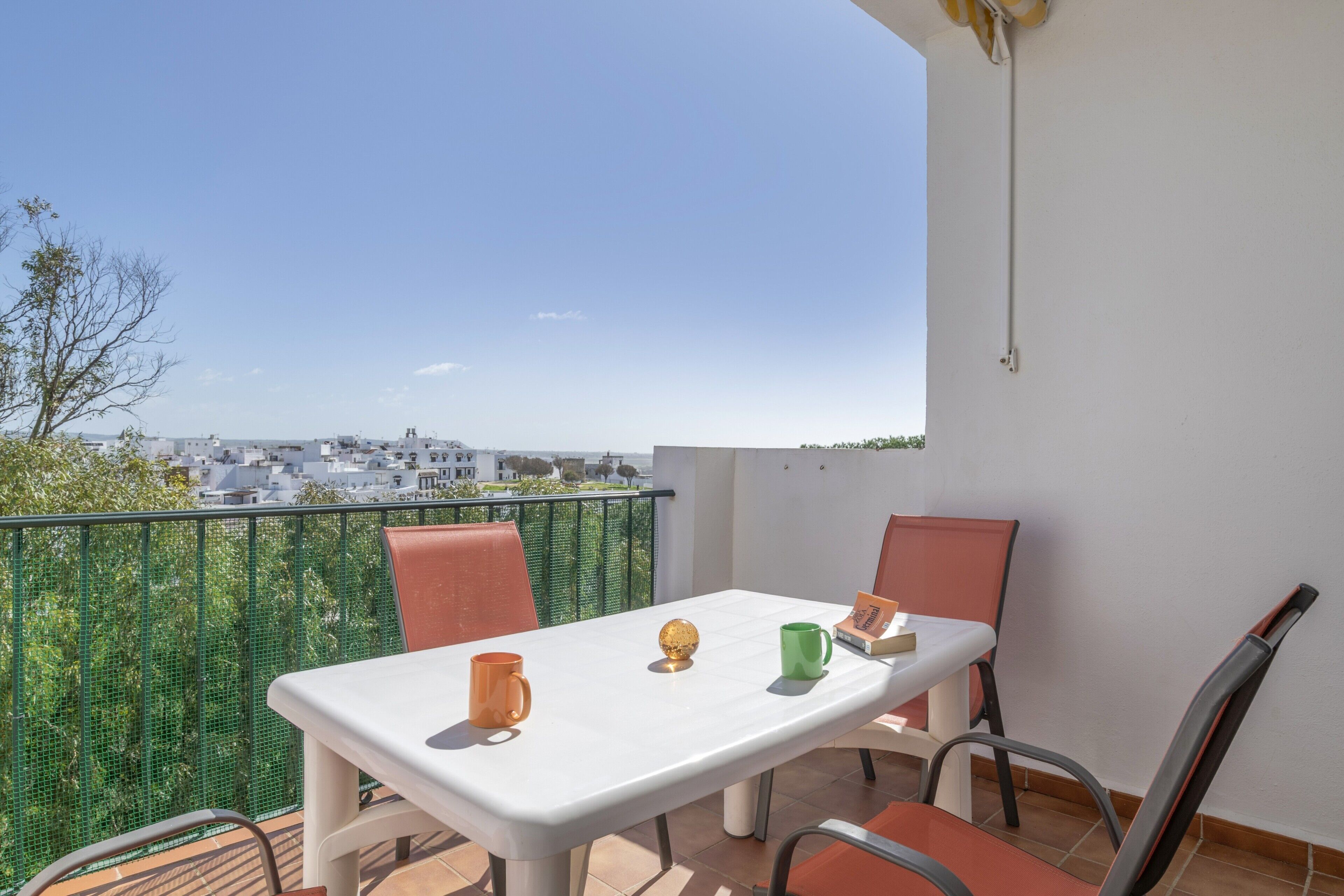 Ein Balkon mit Tisch, Stühlen und Blick auf Gebäude.