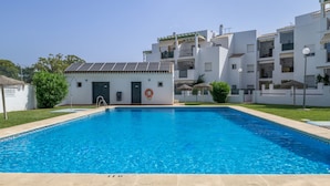 Une piscine avec une bouée de sauvetage, un petit bâtiment et, au fond, des immeubles d’habitation blancs.