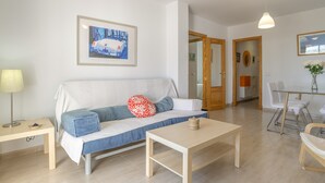 Un salon moderne comprenant un canapé, une table basse et un coin repas avec des chaises et une table en verre.