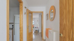 Un couloir avec un coin cuisine, des portes en bois et un radiateur.