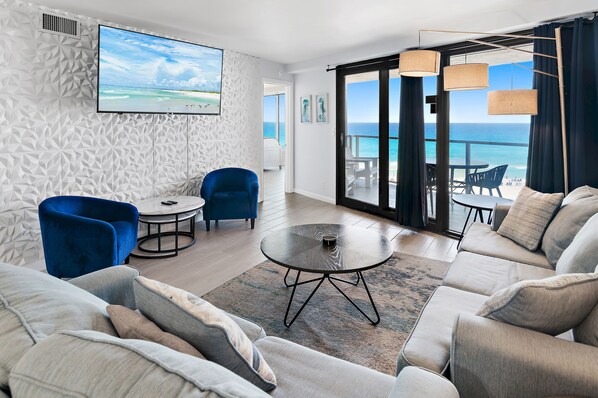 A modern living room with a sofa, a round coffee table, a blue armchair, and a TV on the wall. - 🌴Stunning Beachfront Views | Pool | Beachside II #4260🌴 (Miramar Beach)