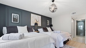 Ein modernes Hotelzimmer mit zwei Betten, einem großen abstrakten Gemälde, einer Stehlampe und Blick auf die Stadt durch eine Glastür.
