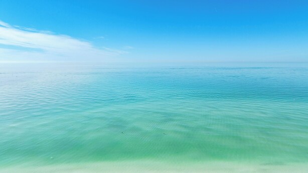 Ein klarer Blick auf ein ruhiges Meer mit sanften Wellen und einem wolkenlosen Himmel.